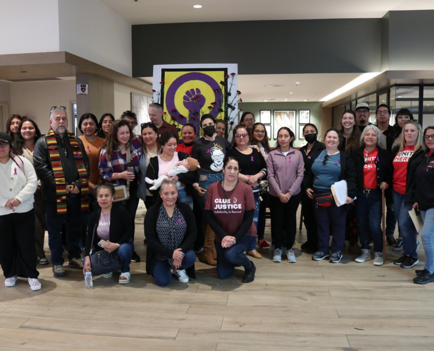 Dozens of hotel workers gather in the lobby of the Sheraton Park Anaheim hotel in front of a purple fist painted in honor of International Women's Day