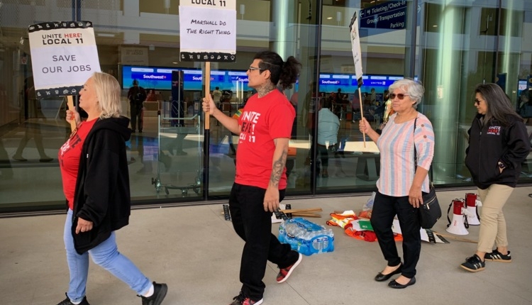 Retail workers picket outside the brand-new Hollywood Burbank airport terminal with signs reading "Save our Jobs" and "Marshall do the right thing"