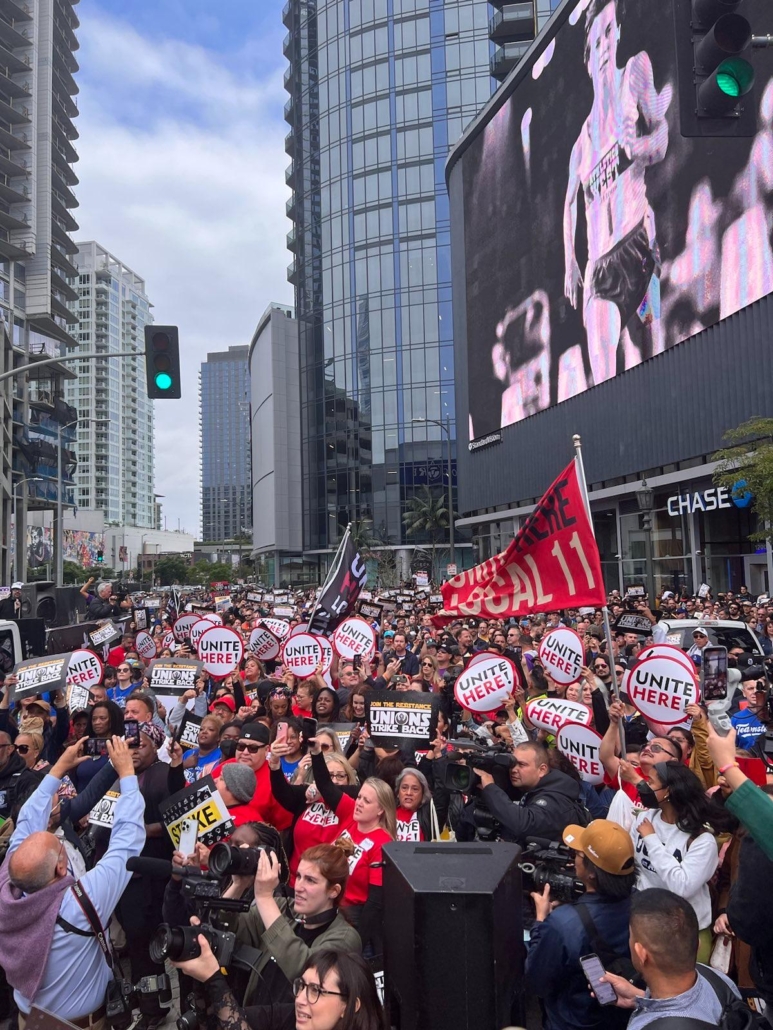 A crowd of workers from industries as diverse as Hollywood writers, teachers, hospitality workers, and delivery drivers rally in downtown Los Angeles