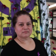 Sheraton Park Anaheim employee Margarita Virrueta de Garibay poses in front of a purple fist painted to honor International Women's Day