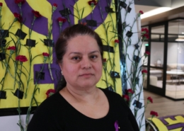 Sheraton Park Anaheim employee Margarita Virrueta de Garibay poses in front of a purple fist painted to honor International Women's Day