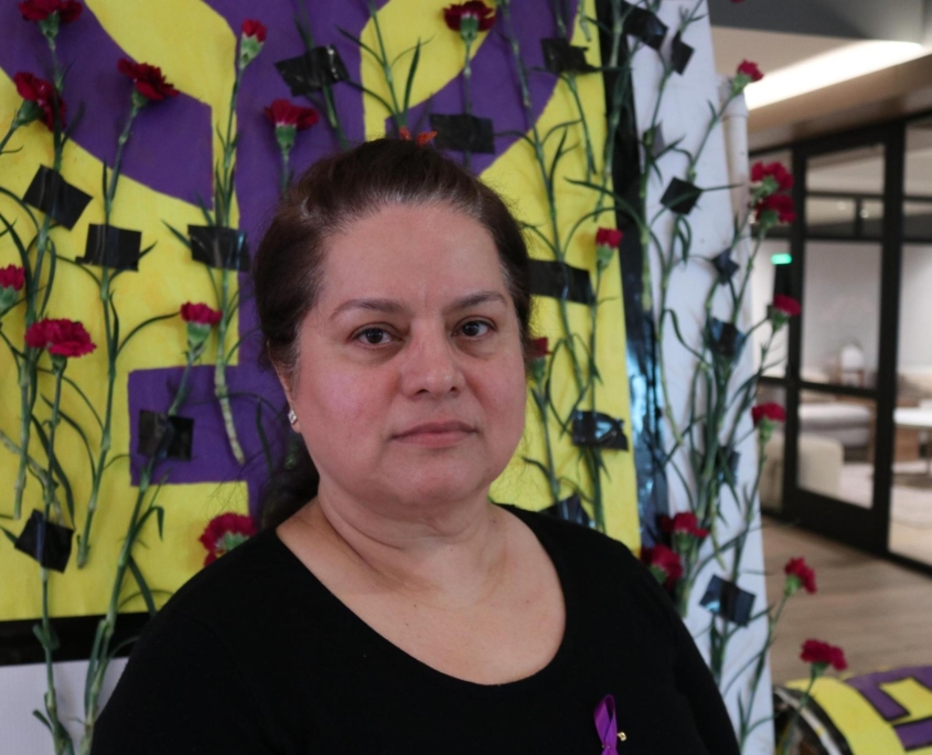Sheraton Park Anaheim employee Margarita Virrueta de Garibay poses in front of a purple fist painted to honor International Women's Day