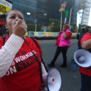 Two striking hotel workers in red t-shirts lead chants on the bullhorn