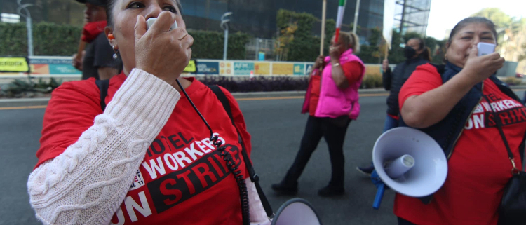 Two striking hotel workers in red t-shirts lead chants on the bullhorn